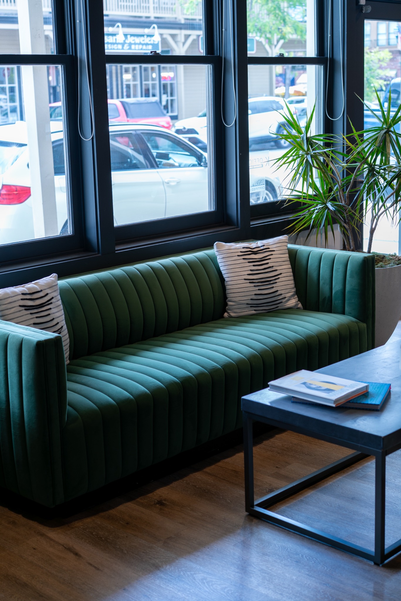 Modern salon lounge with green velvet seating and natural light