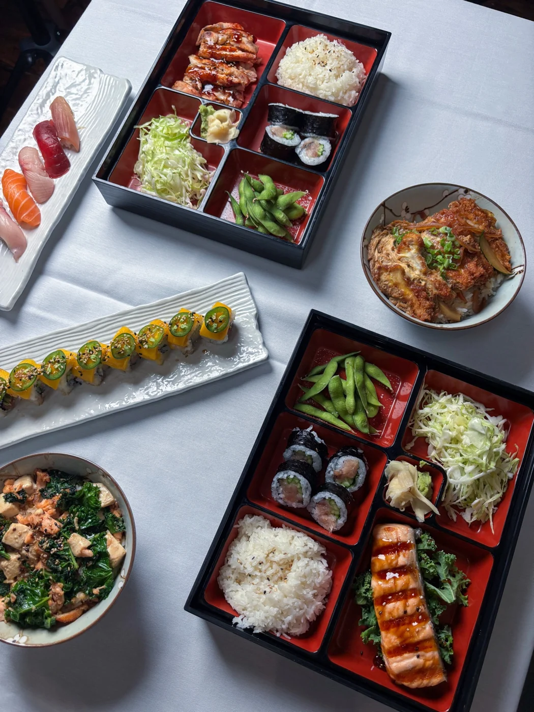 Overhead spread of Kakui bento boxes and sushi rolls