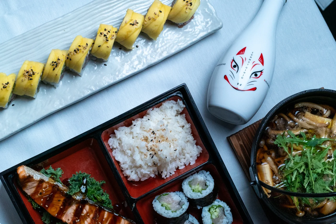 Kakui lunch spread with sushi, bento and a Japanese fox mask